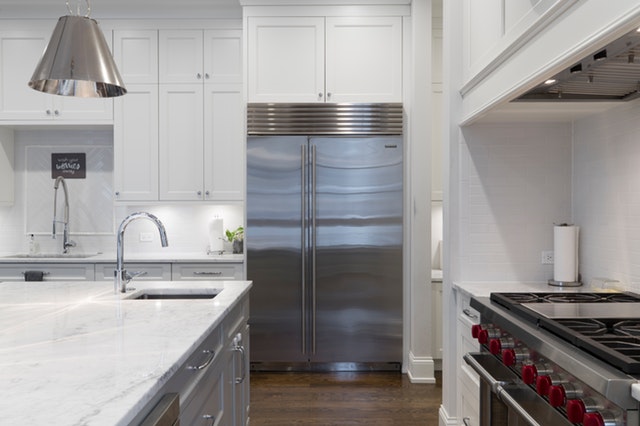 interior of a modern kitchen with marble countertops and chrome appliances